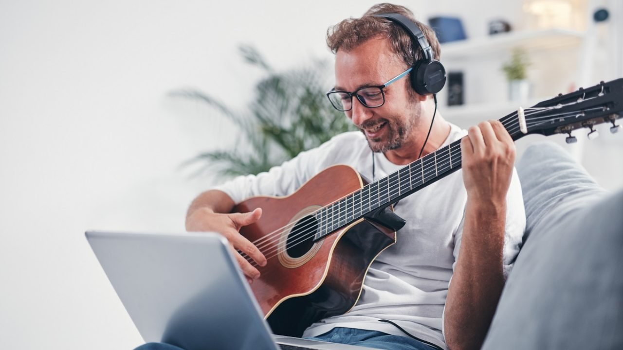 Man playing acoustic guitar in the living room.